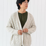 Male model wearing the Chunky Cable Knit Cardigan in Oat paired with Henley and dark pants