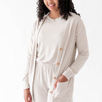 Model wearing the Bamboo Jersey Adult Cardigan in Oat overtop an Oat shirt and Oat pants