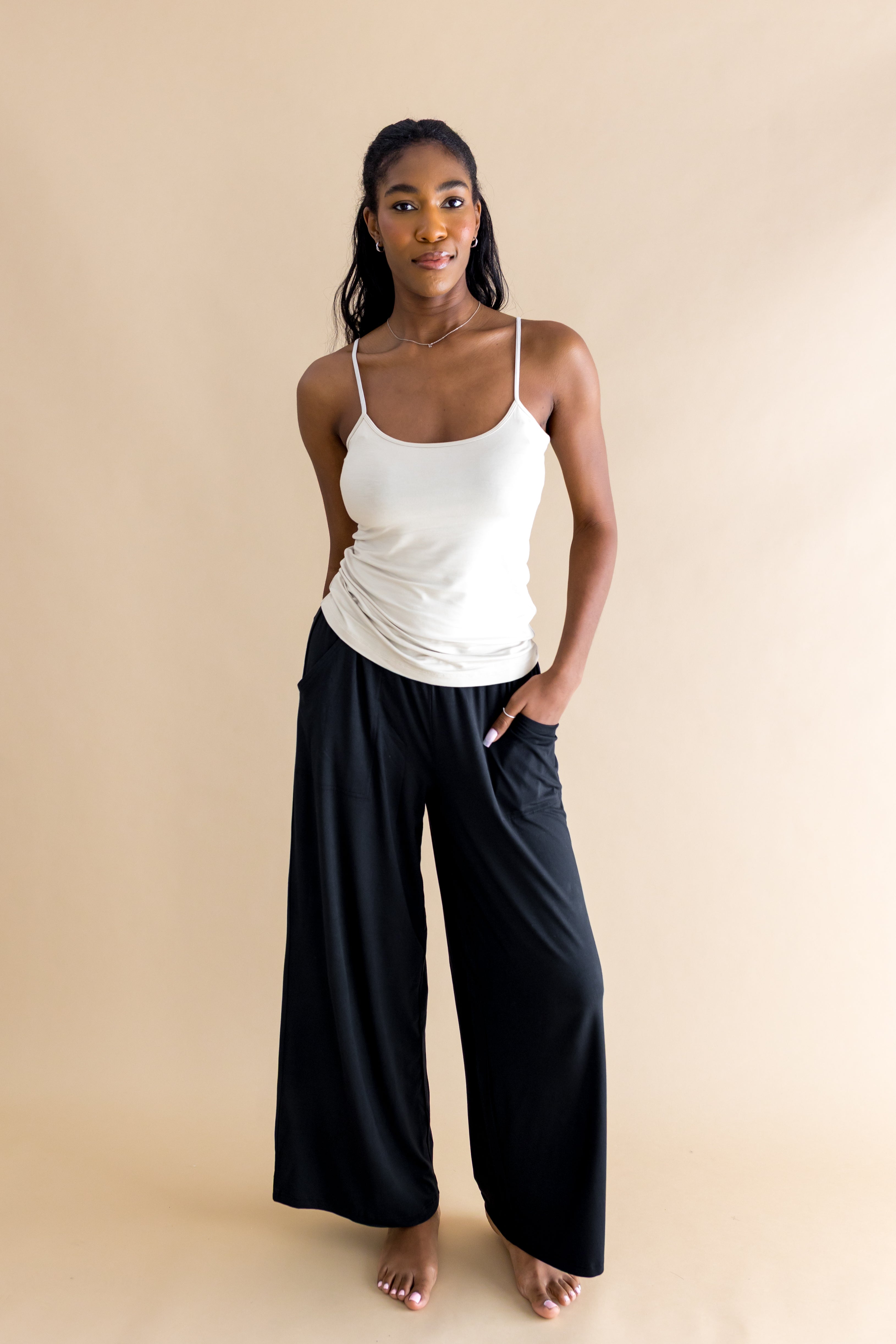 Woman wearing a beige tank top and black wide-leg pants on a beige background ::: Model is 5'9" wearing size S ///