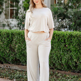woman modeling a creamy off white wide leg pant and cropped tee in an outdoor setting
