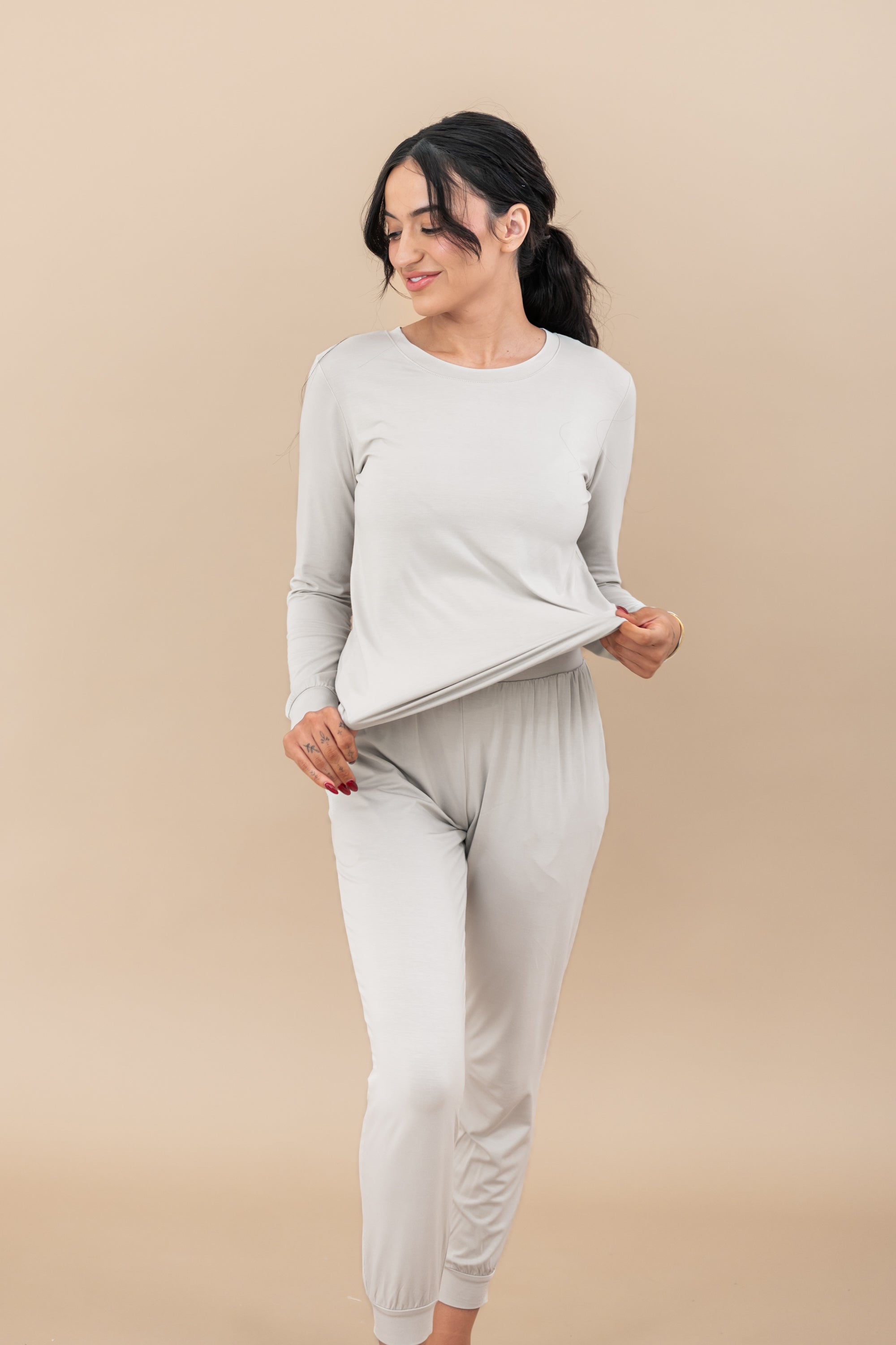 Model stretching the jogger top to show how much elasticity is in the fabric wearing the Women's Jogger Pajama Set in Oat