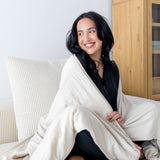Woman cozy with a cream colored throw blanket around shoulders