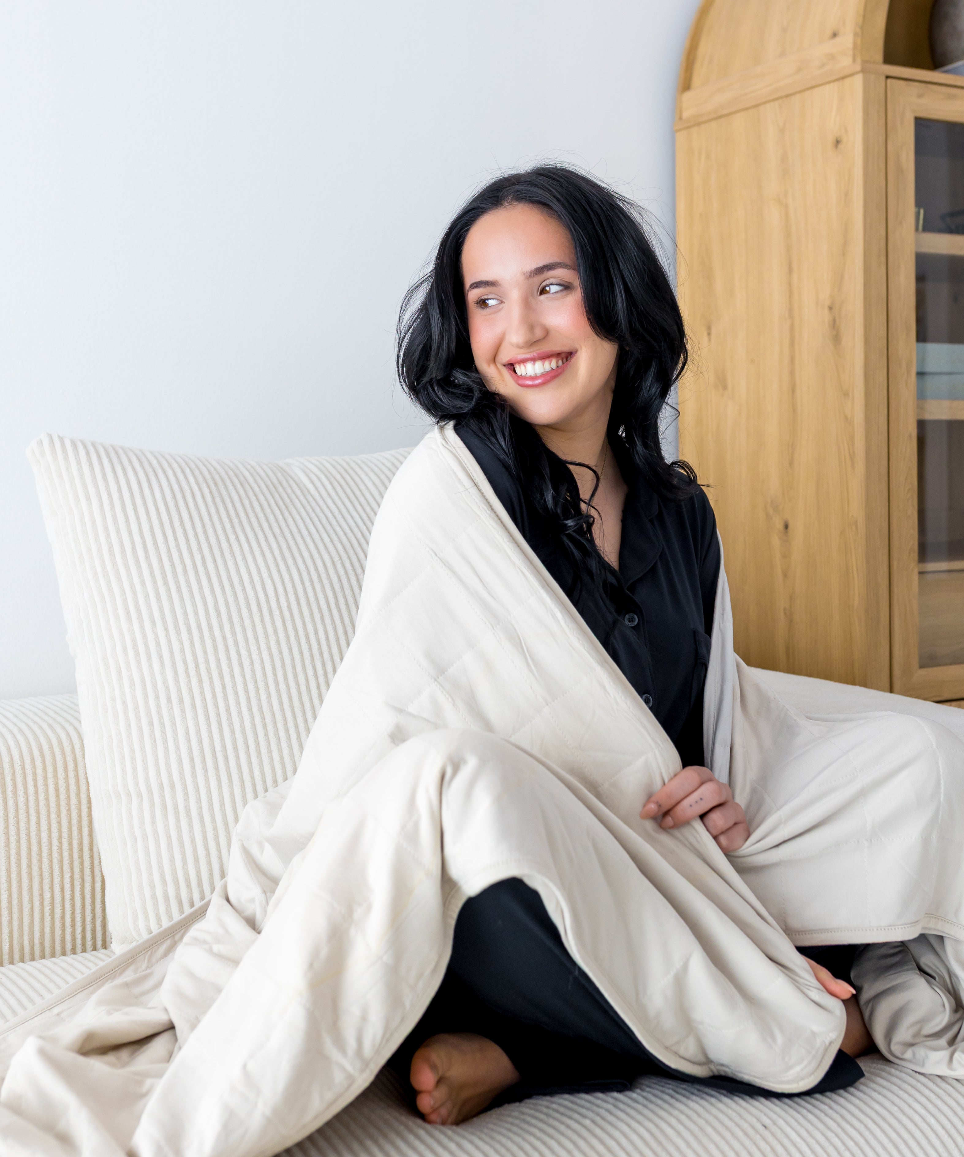 Woman cozy with a cream colored throw blanket around shoulders