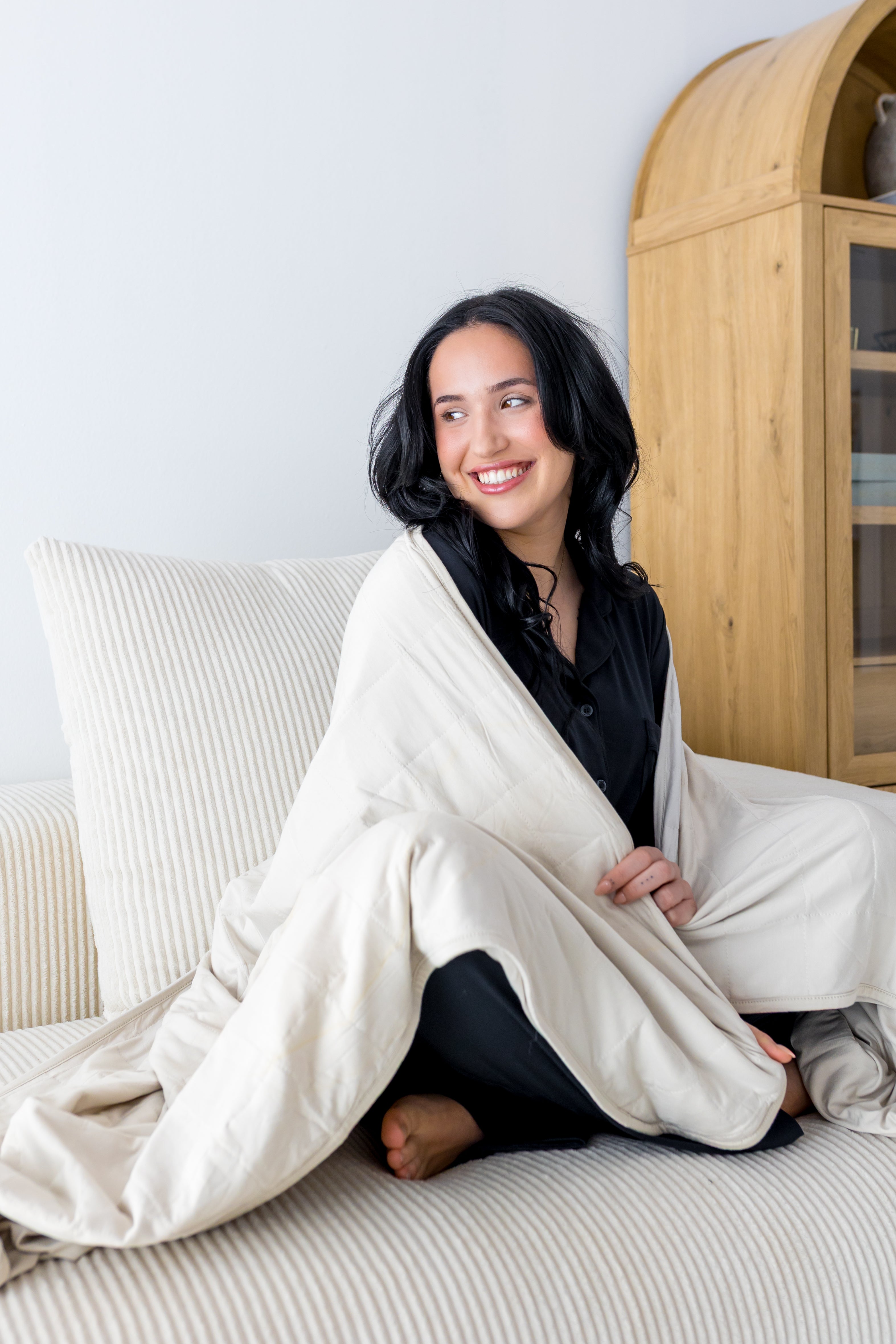 Woman cozy with a cream colored throw blanket around shoulders