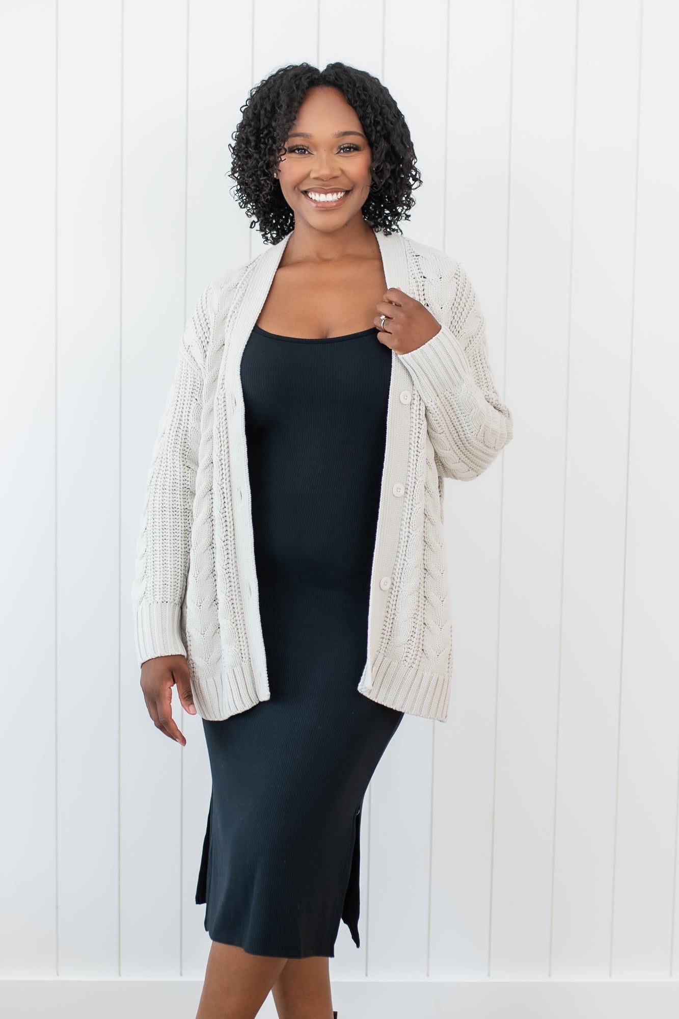 Model wearing the Chunky Cable Knit Cardigan in Oat layered over the Ribbed Cami dress in Midnight