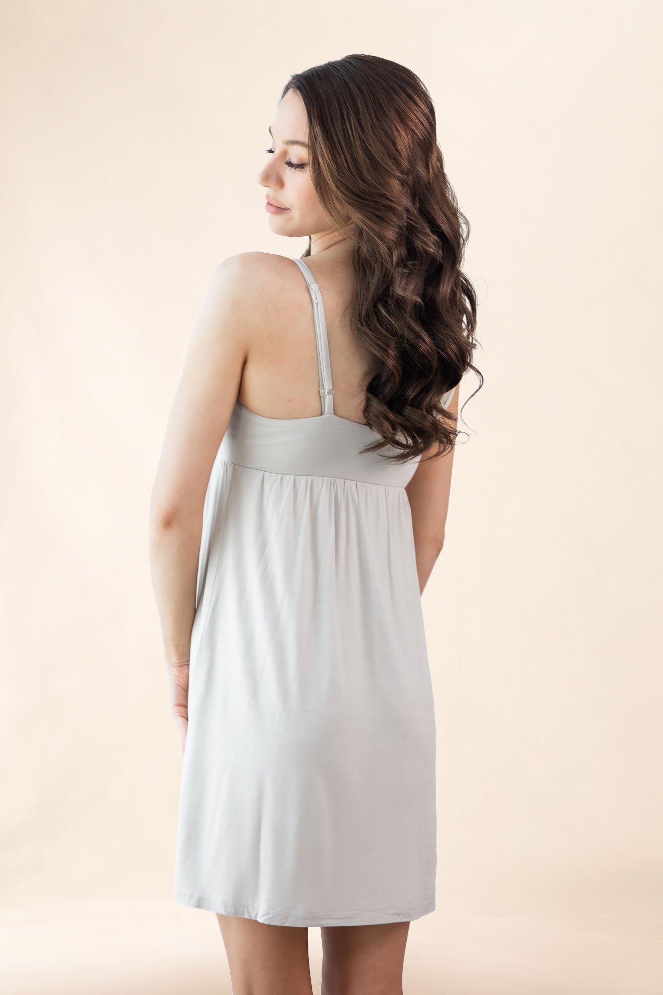 Woman wearing a light gray nightgown against a beige background