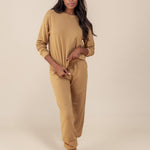 Modal wearing Women's Jogger Pants in Ochre color under similar color women's sweatshirt on a beige background