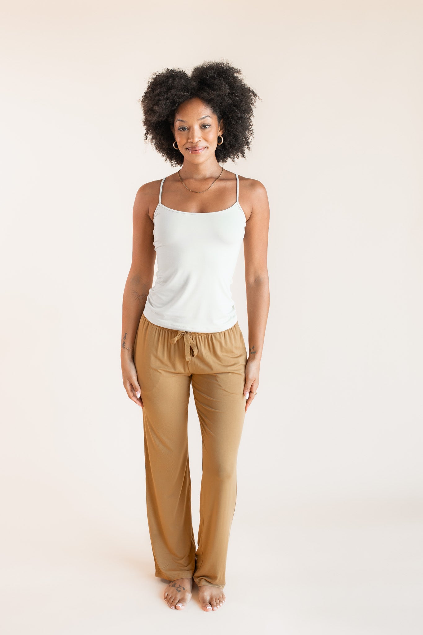 Model wearing Women's Lounge Pants in Ochre under white camisole on a beige background
