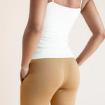 Model showcasing the backside of Women's Lounge Pants in Ochre under white camisole on a beige background