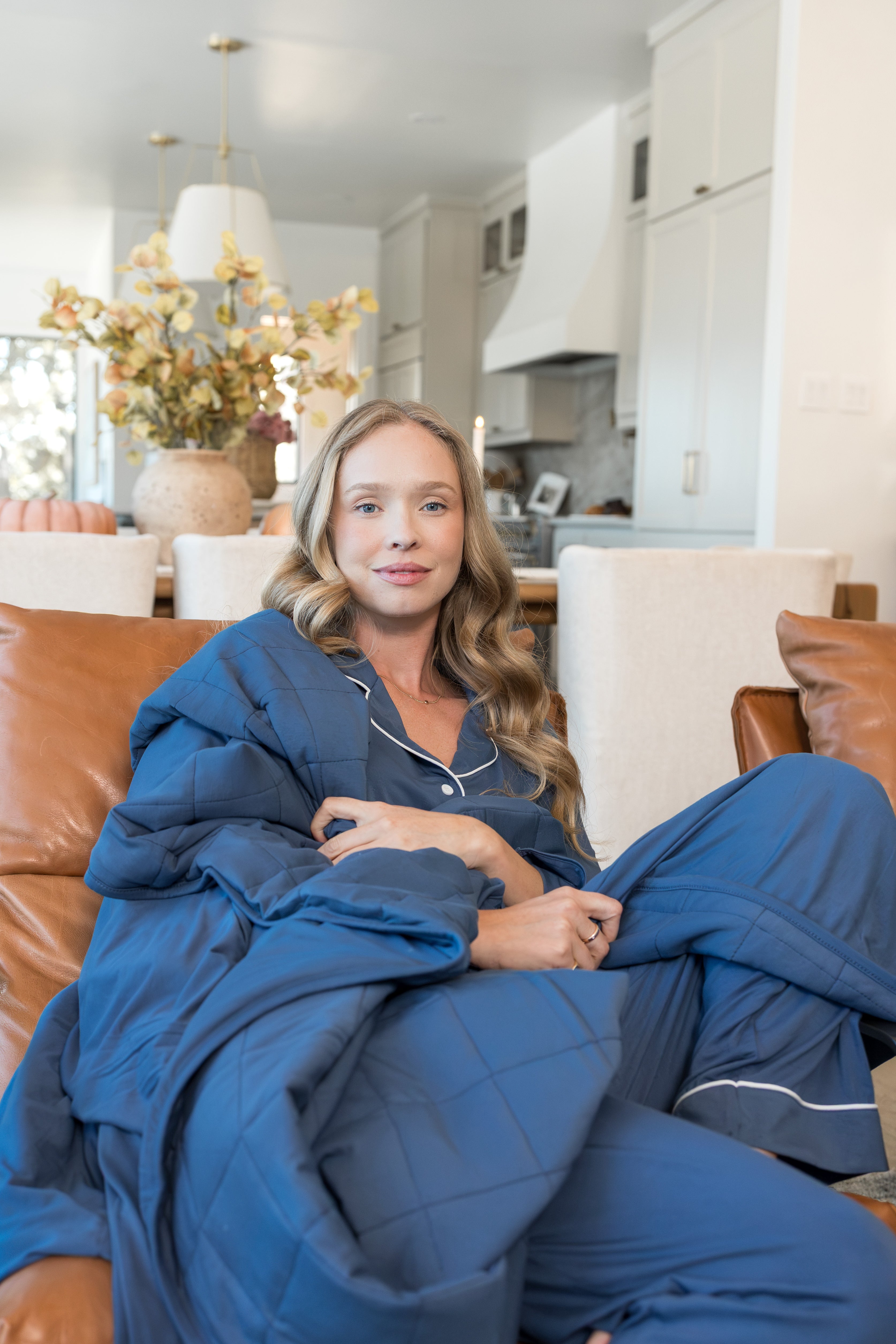 Model sitting on couch with Adult Quilted Blanket in Oxford 2.5