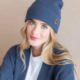 Modal wearing Chunky Knit Adult Pom beanie in Oxford over white t-shirt and chunky knit women's cardigan in oxford on a beige background