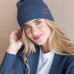 Modal wearing Chunky Knit Adult Pom Beanie in Oxford over white t-shirt and chunky knit women's cardigan in oxford on a beige background