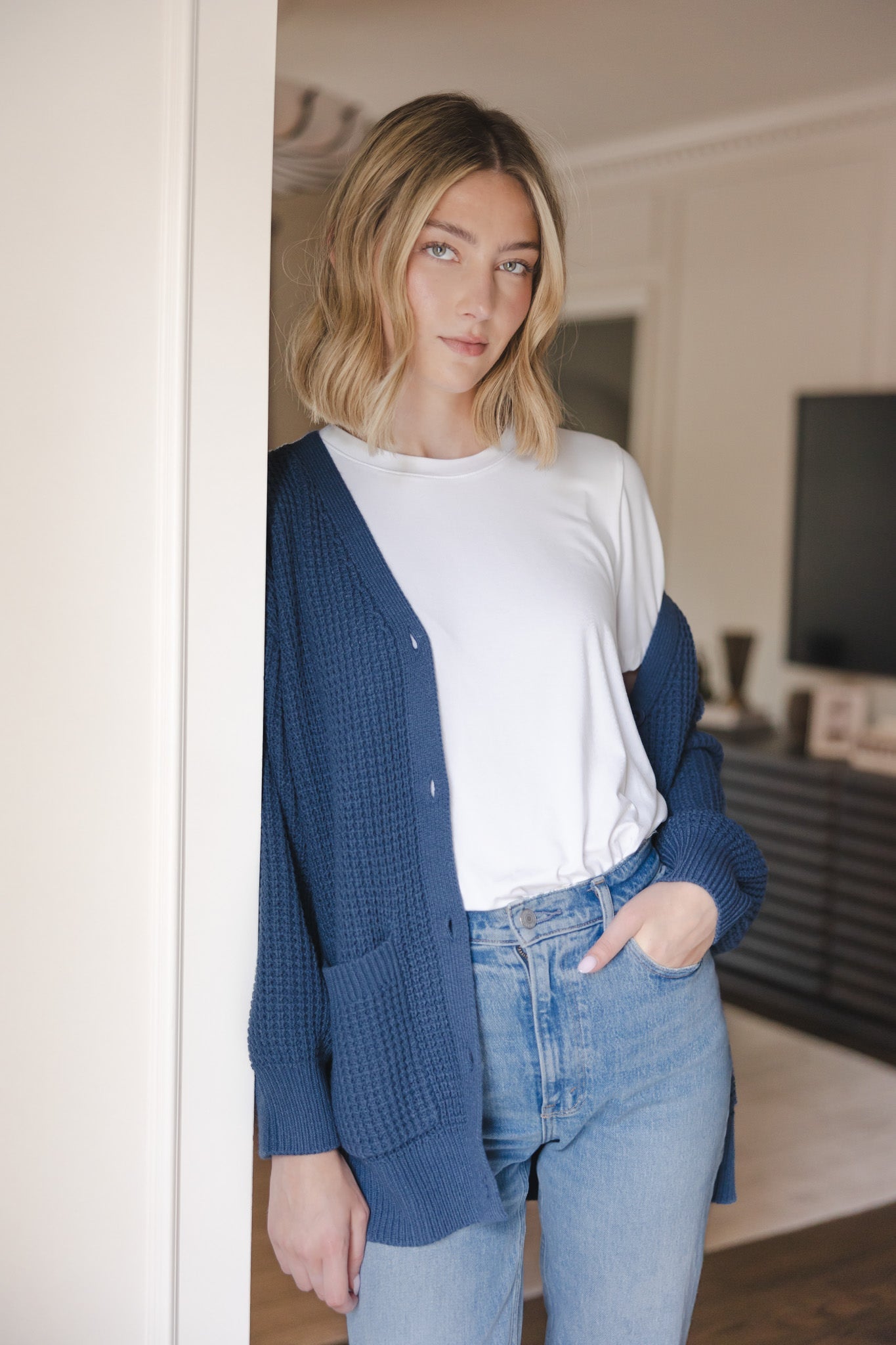 Modal posing wearing Chunky Knit Women's Waffle Cardigan in Oxford over white t-shirt and blue jeans