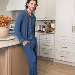 Male model wearing oxford blue button up long sleeve pajamas in a kitchen