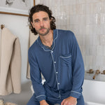 Male model wearing oxford blue button up long sleeve pajamas in a bathroom