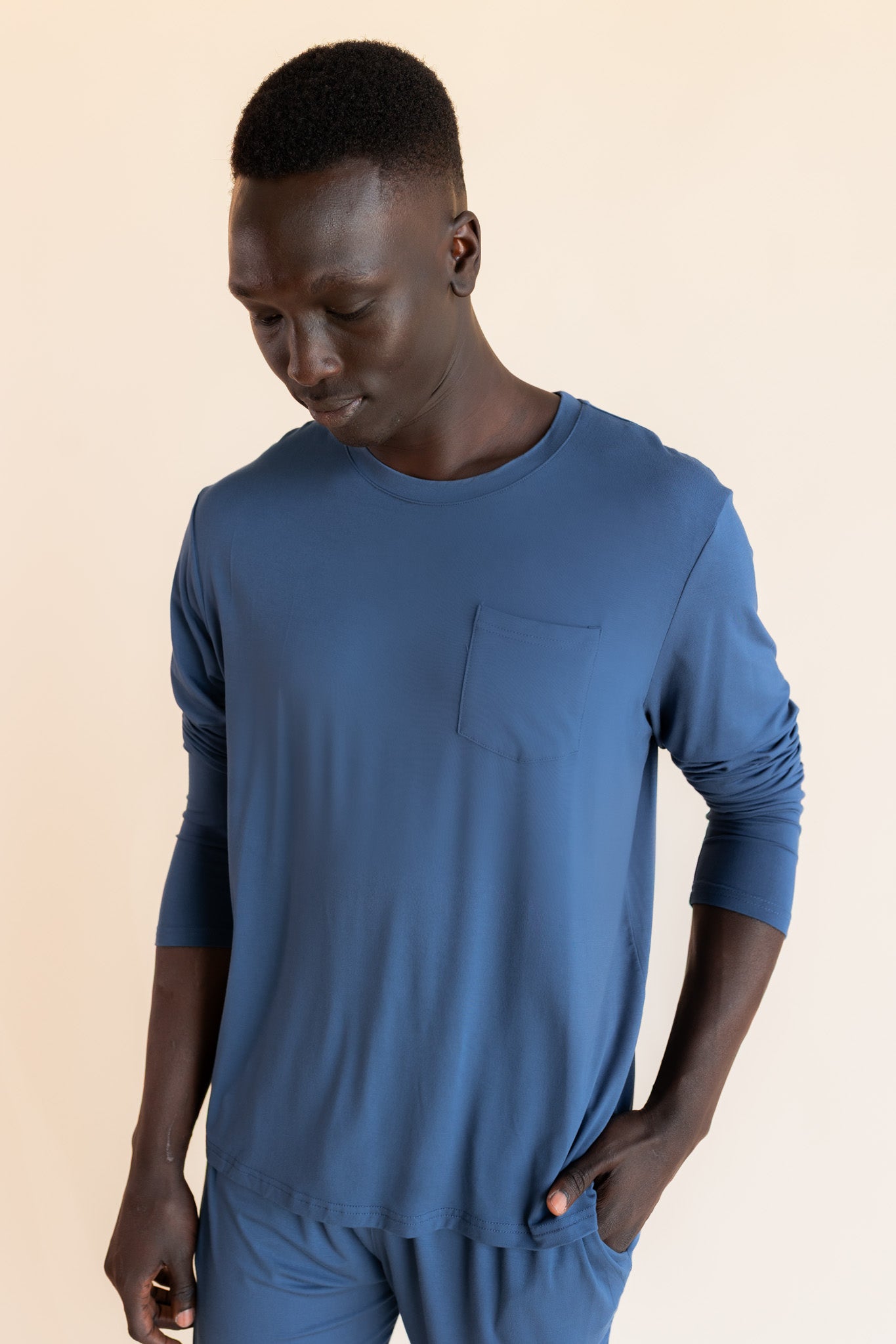 Male model wearing oxford blue jogger set in a studio setting, with hand in pocket