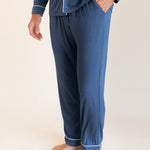 Male model wearing oxford blue button up long sleeve pajamas in a studio setting, close up on pant and pocket