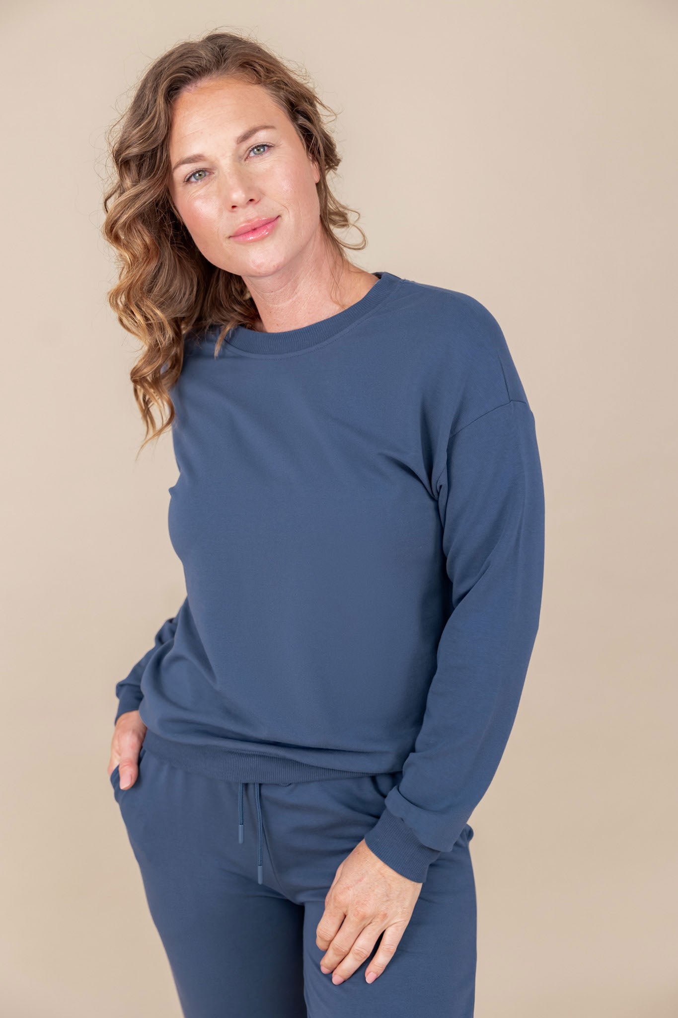 Woman wearing a oxford blue crew neck sweatshirt and matching pant 