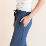 Model showcasing pockets on Women's Lounge Pants in Oxford under white camisole on a beige background