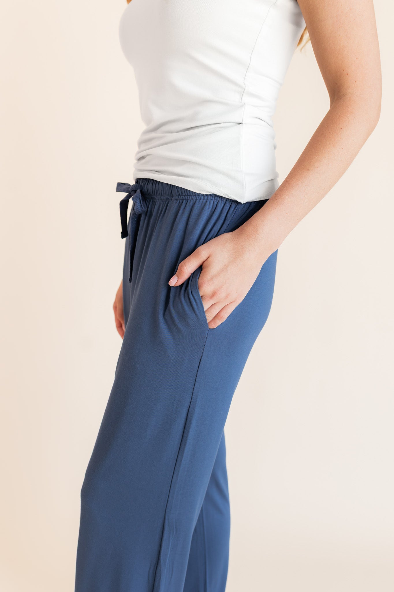 Model showcasing pockets on Women's Lounge Pants in Oxford under white camisole on a beige background