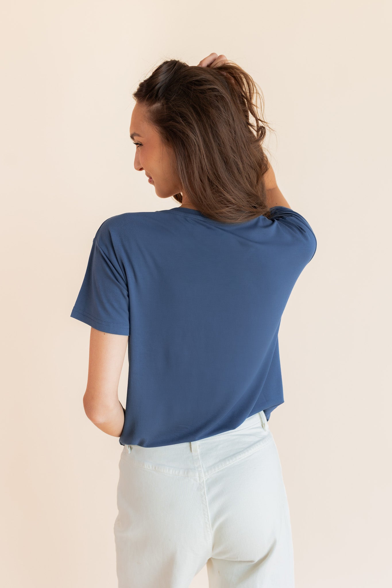Woman modeling a oxford blue v-neck oversized tee, showing back