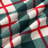 A close-up of draped fabric with a green, white, and red plaid pattern.
