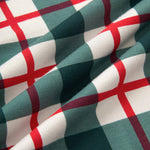 A close-up of draped fabric with a green, white, and red plaid pattern.