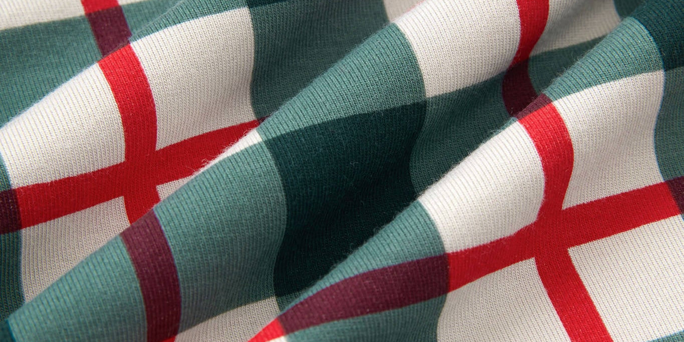 A close-up of draped fabric with a green, white, and red plaid pattern.