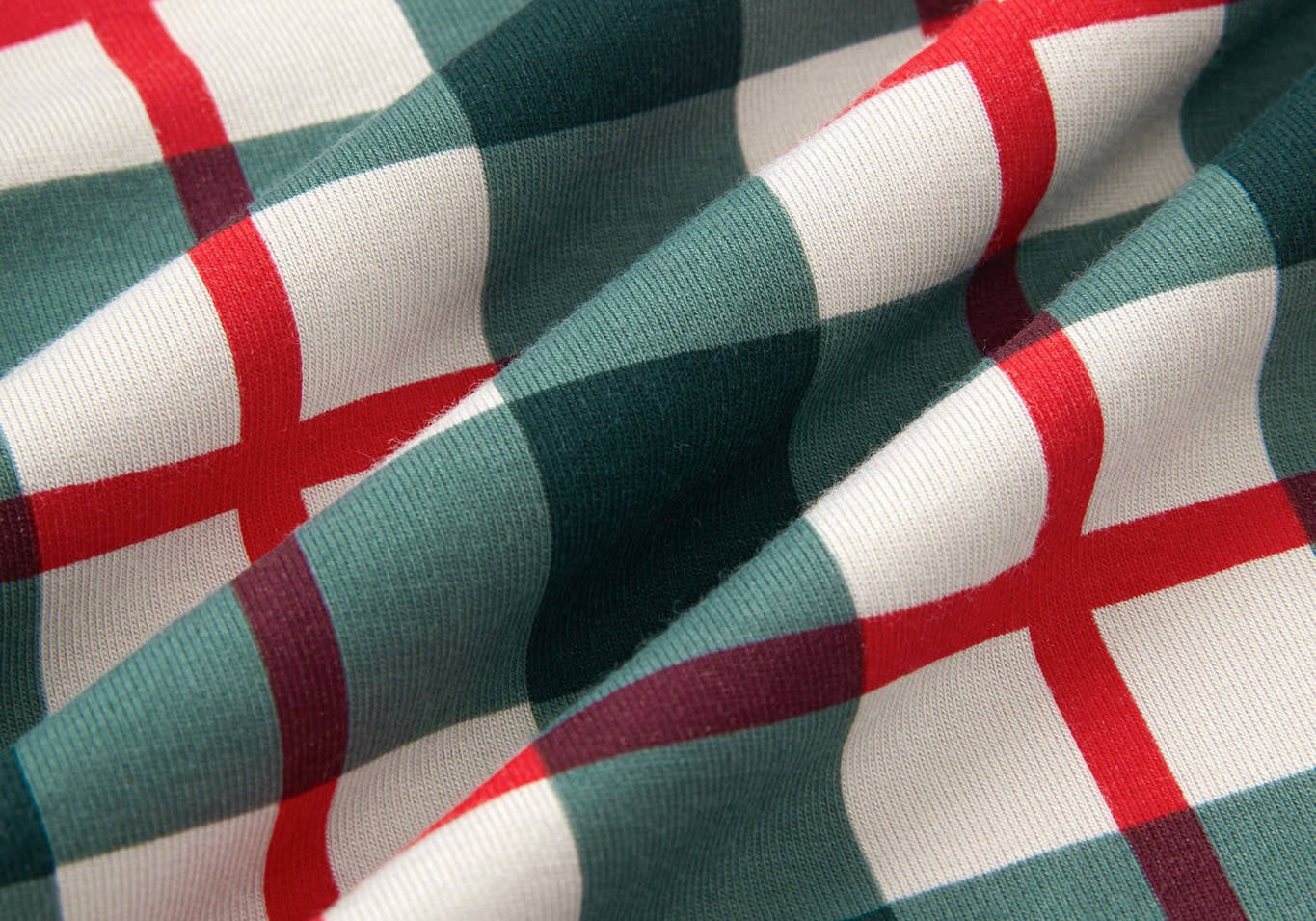 A close-up of draped fabric with a green, white, and red plaid pattern.