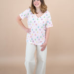 Woman standing with hand on hip while modeling the Women's V Neck in Pastel Ghost paired with Khaki pants