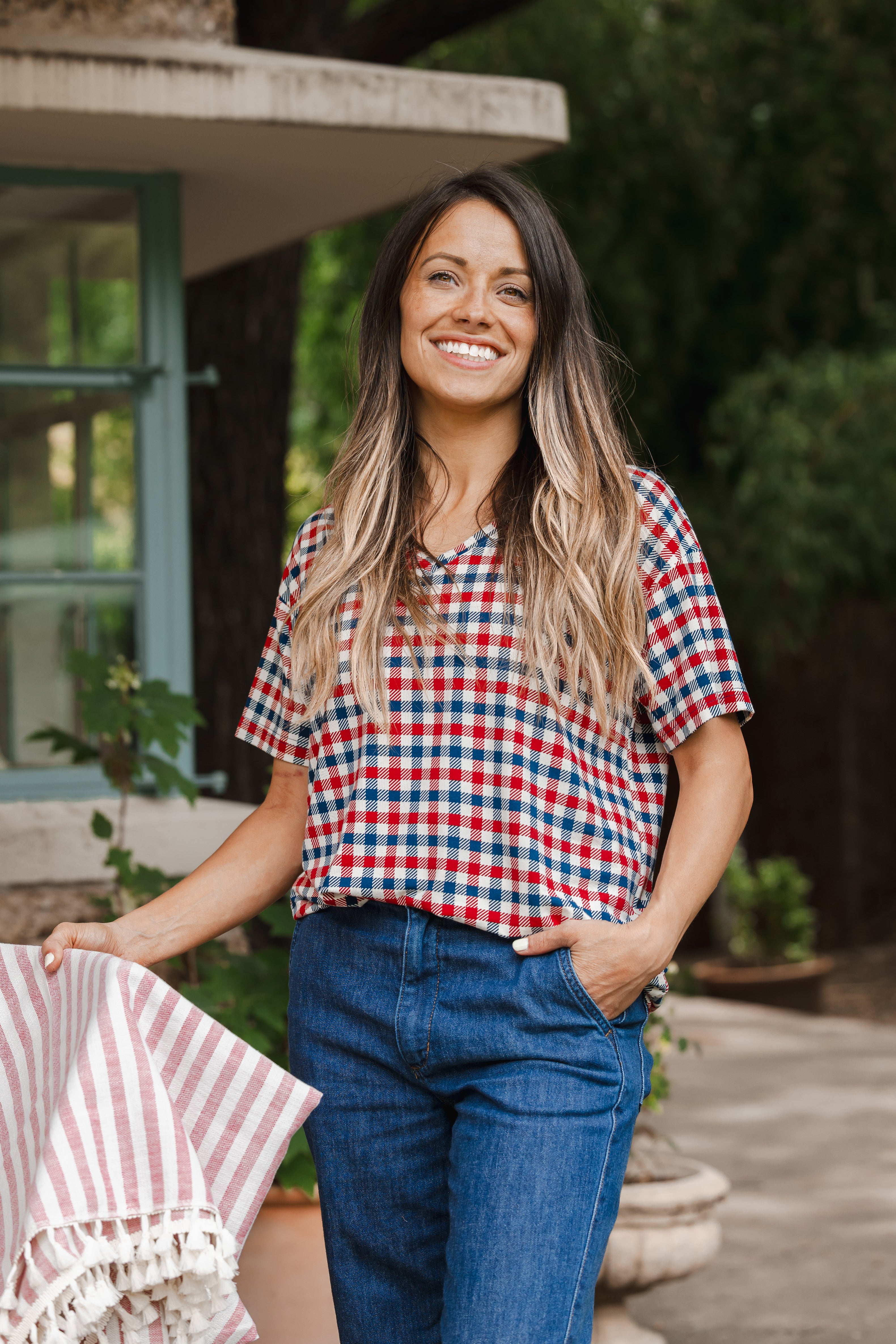 Model standing outdoors wearing Women's Relaxed Fit V-Neck in Patriotic Gingham over denim pants