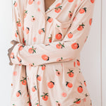 Woman wearing long sleeve button up pajamas in a peach print
