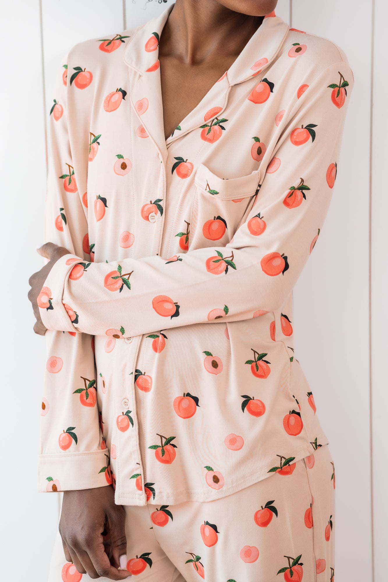Woman wearing long sleeve button up pajamas in a peach print