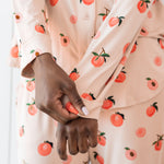 Woman wearing long sleeve button up pajamas in a peach print showing cuff of top