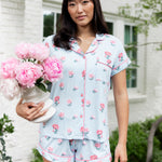 Woman outside soft smiling holding a vase of flowers in short sleeve pajamas and shorts in Peony on Breeze print. ---PJ 4