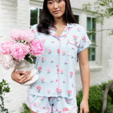 Woman outside soft smiling holding a vase of flowers in short sleeve pajamas and shorts in Peony on Breeze print. ---PJ 4