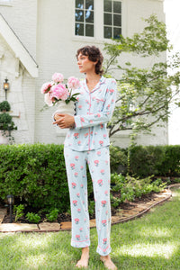 Woman outside looking over holding a vase of flowers wearing long sleeve  pajamas and pants in Peony on Breeze print. ---1605 1