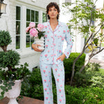 Woman outside holding a vase of flowers with the other hand in her pocket wearing long sleeve pajamas and pants in Peony on Breeze print. ---1605 3