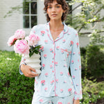 Woman outside soft smiling holding a vase of flowers in long sleeve pajamas and pants in Peony on Breeze print. ---PJ 4