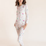 A woman modeling a two-piece long-sleeve pajama set with a colorful pickleball print on a light cream background, set against a solid warm beige studio backdrop.
::: Model is 5'9.5" wearing size XS ///