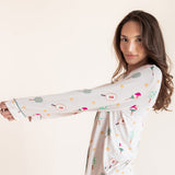 A woman modeling a long-sleeve white pajama set with a colorful pickleball  print, posed against a solid light beige background.
---1605 1