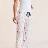 A woman modeling white pajama pants with a colorful pickleball pattern, paired with a white tank top, against a solid beige background.
::: Model is 5'9"" wearing size S ///