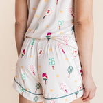 A person wearing a matching two-piece pajama set with a cream background and a colorful pickleball pattern, shown from the back against a plain beige studio background.