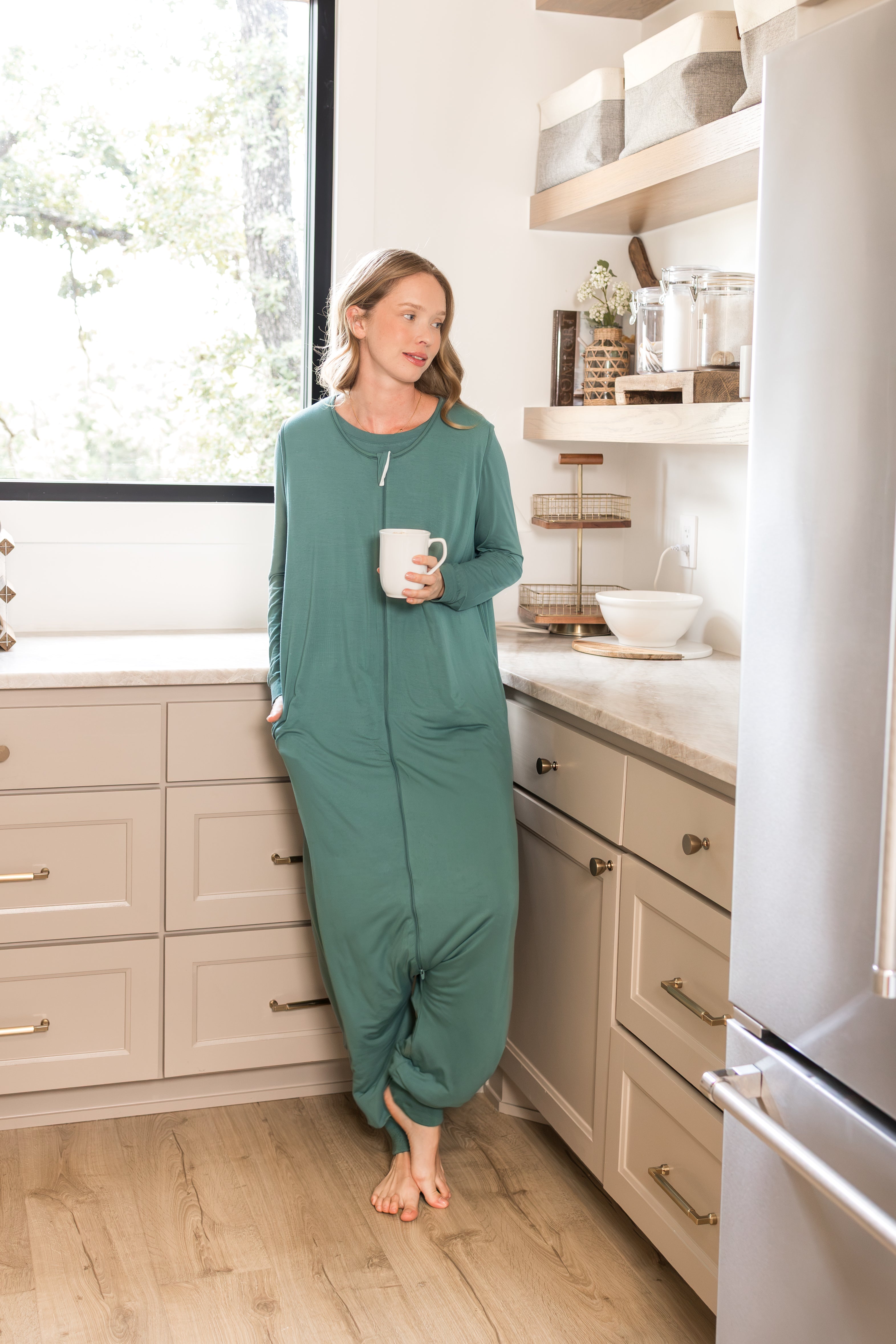 Model wearing Adult Sleep Sack in Pine holding a mug in kitchen
::: Model is 5'10" wearing size S/M ///
