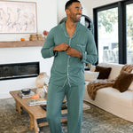 Male model wearing muted sage green button up long sleeve pajamas in a luxury living room