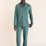 Male model wearing muted sage green button up long sleeve pajamas in a studio setting