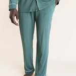 Male model wearing muted sage green button up long sleeve pajamas in a studio setting, close up on pant