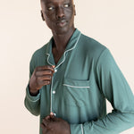 Male model wearing muted sage green button up long sleeve pajamas in a studio setting, close up on buttons