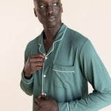 Male model wearing muted sage green button up long sleeve pajamas in a studio setting, close up on buttons