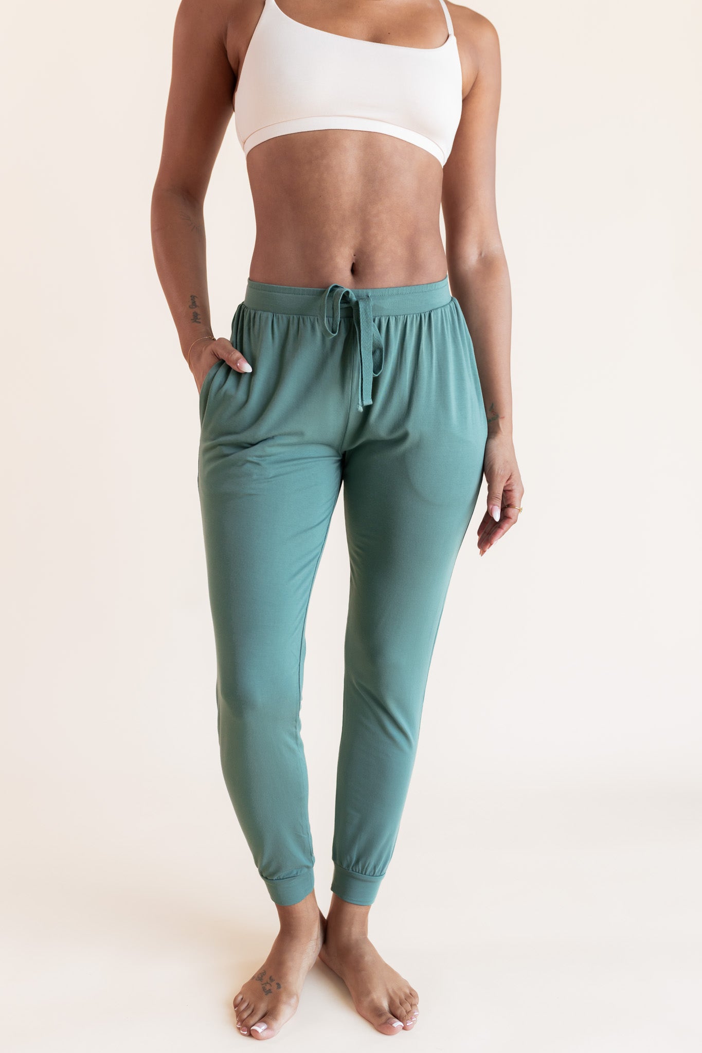 Model wearing sage green jogger pant with drawstring waist and neutral bralette, with hand in pocket
::: Model is 5'9"" wearing size S ///
